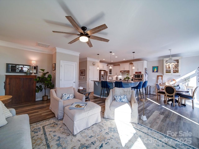 living room with a ceiling fan, visible vents, crown molding, and wood finished floors