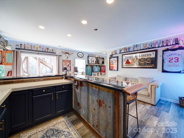 kitchen with light wood-type flooring, light countertops, a breakfast bar area, and recessed lighting