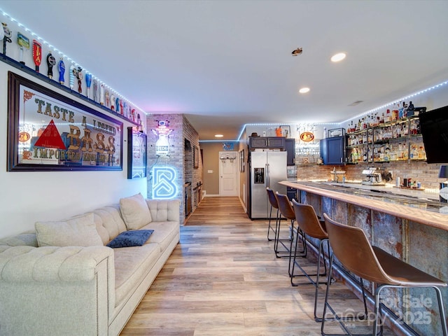 bar with stainless steel fridge, indoor wet bar, light wood-type flooring, backsplash, and recessed lighting