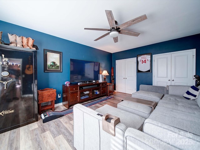 living area featuring a ceiling fan, baseboards, and wood finished floors