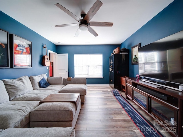 living room with wood finished floors, a ceiling fan, and baseboards