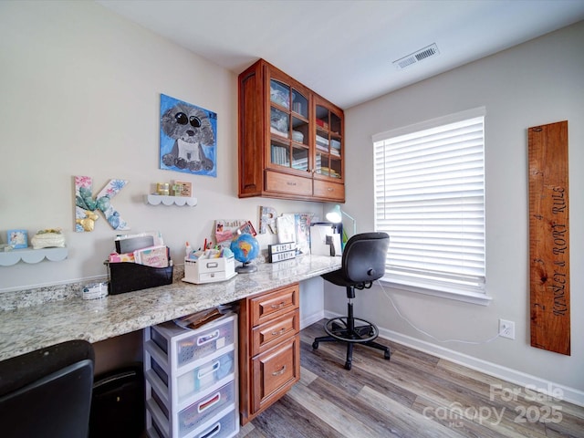 office space featuring built in desk, wood finished floors, visible vents, and baseboards