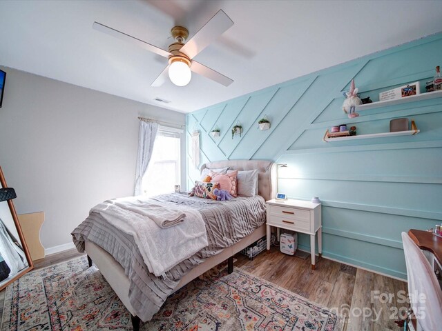 bedroom featuring visible vents, ceiling fan, baseboards, and wood finished floors