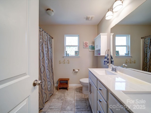 bathroom featuring toilet, plenty of natural light, baseboards, and vanity