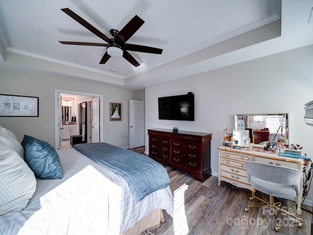 bedroom with a tray ceiling, ornamental molding, ceiling fan, connected bathroom, and wood finished floors