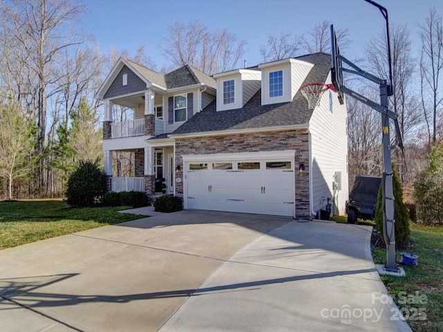 view of front of home with a shingled roof, an attached garage, a balcony, stone siding, and driveway