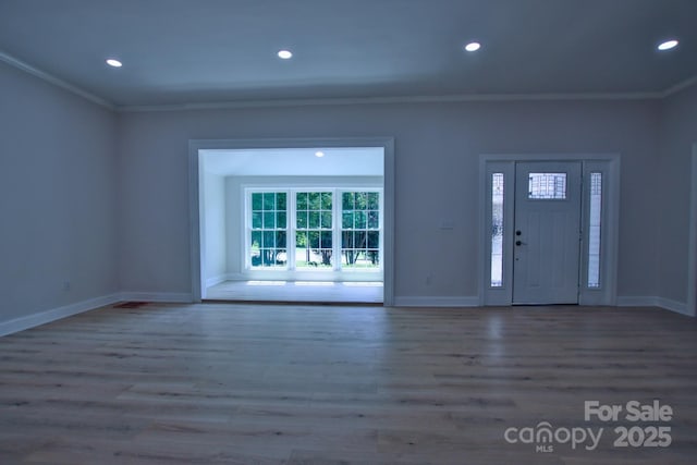 foyer entrance with wood finished floors, ornamental molding, and baseboards