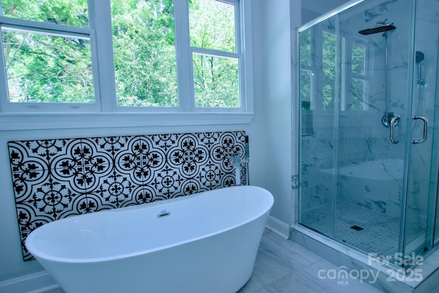bathroom featuring a marble finish shower, a soaking tub, and baseboards