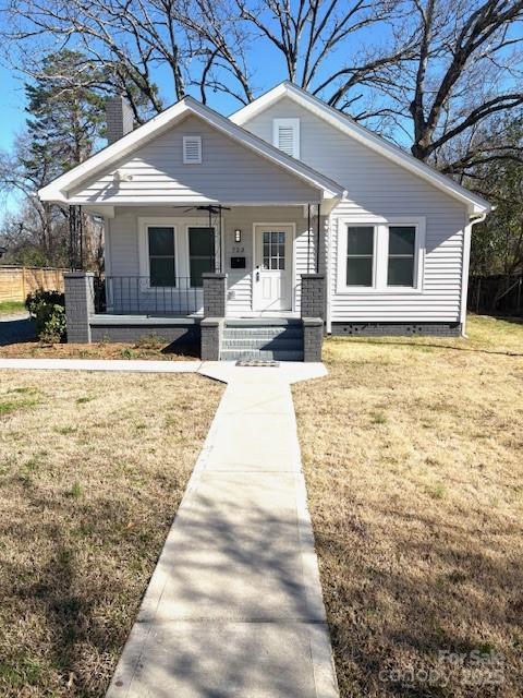 bungalow-style home featuring covered porch, a front lawn, and fence