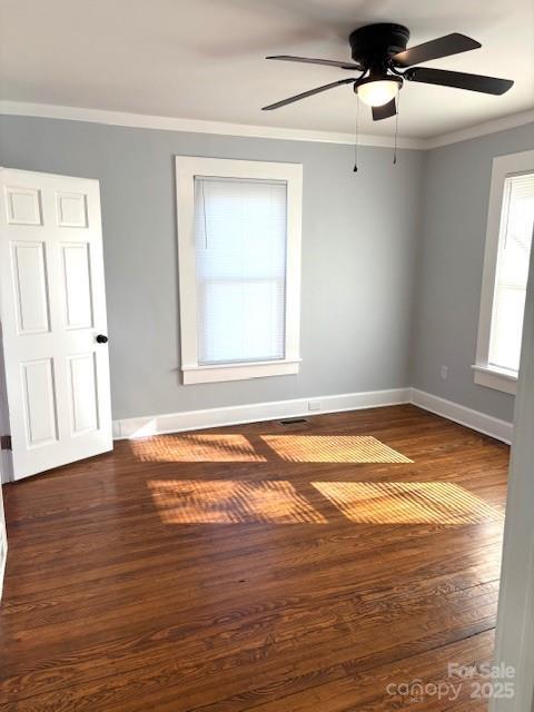 spare room with a ceiling fan, baseboards, crown molding, and wood finished floors