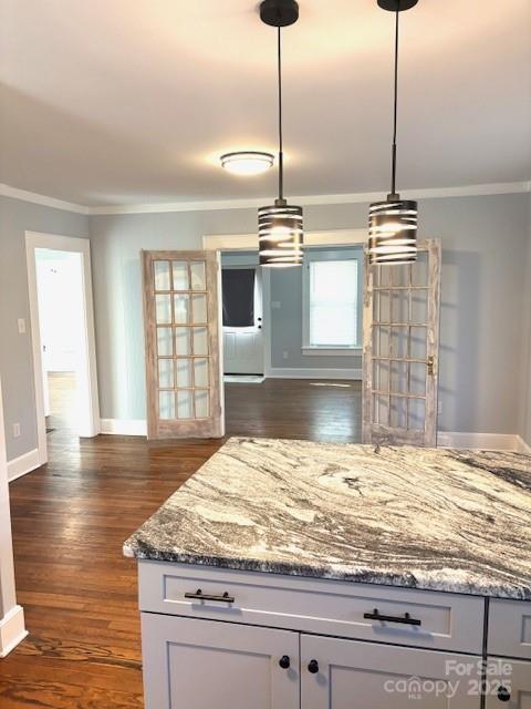 kitchen with stone countertops, dark wood finished floors, crown molding, and baseboards