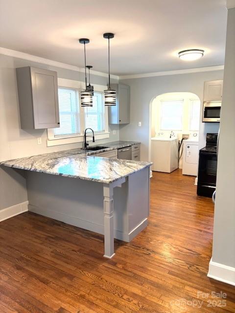 kitchen with gray cabinetry, a peninsula, a sink, appliances with stainless steel finishes, and washing machine and clothes dryer