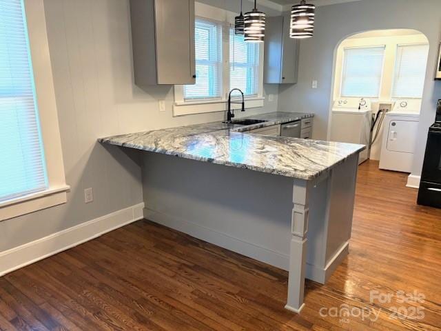 kitchen featuring light stone countertops, washer and clothes dryer, a sink, and gray cabinetry