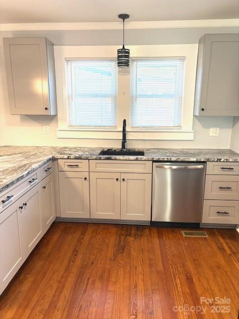 kitchen featuring dark wood-type flooring, a sink, stainless steel dishwasher, light stone countertops, and decorative light fixtures