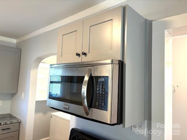 interior details with ornamental molding, gray cabinets, and stainless steel microwave