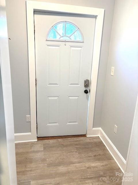 doorway featuring baseboards and wood finished floors