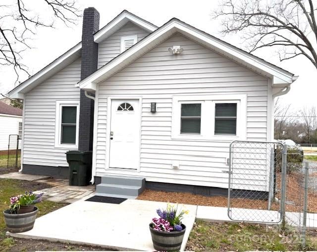 view of front of property featuring entry steps, a chimney, and fence