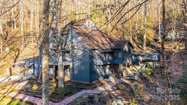 view of side of home with a wooded view and an outdoor structure