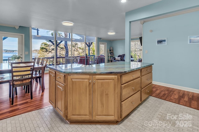 kitchen featuring dark stone counters, a center island, baseboards, and light tile patterned floors