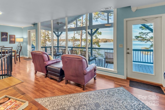 living room featuring a water view, crown molding, baseboards, and wood finished floors