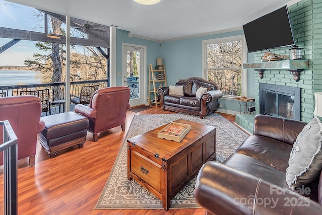 living room with a fireplace, wood finished floors, a wealth of natural light, and crown molding