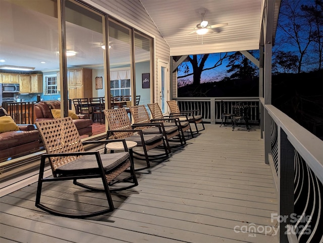 deck at dusk featuring ceiling fan