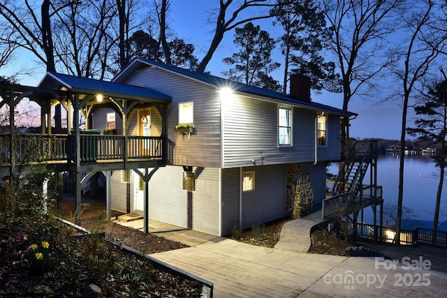 view of home's exterior with a water view, stairs, and a chimney