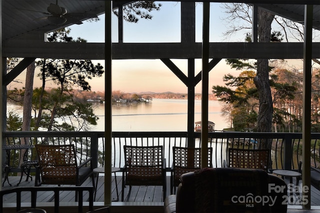 deck at dusk with a ceiling fan and a water view