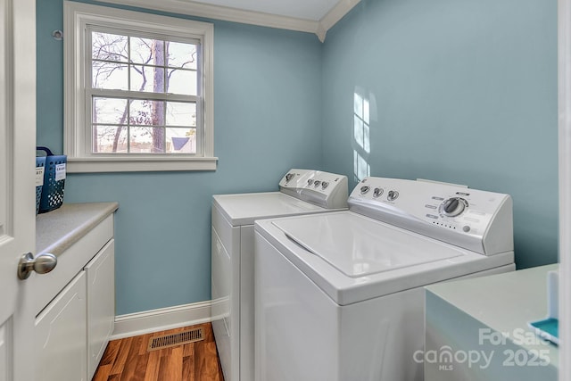 washroom featuring washing machine and dryer, dark wood-type flooring, visible vents, baseboards, and cabinet space