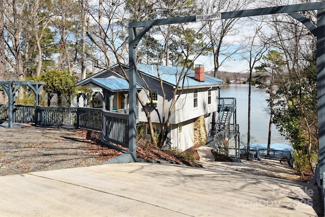 view of front facade featuring stairway, a water view, and a chimney