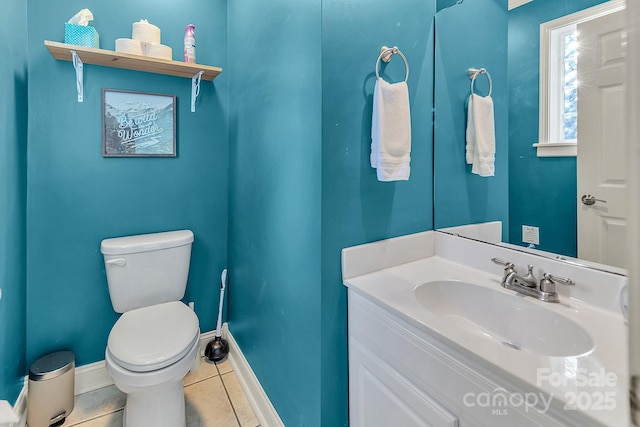 half bathroom featuring toilet, tile patterned flooring, baseboards, and vanity