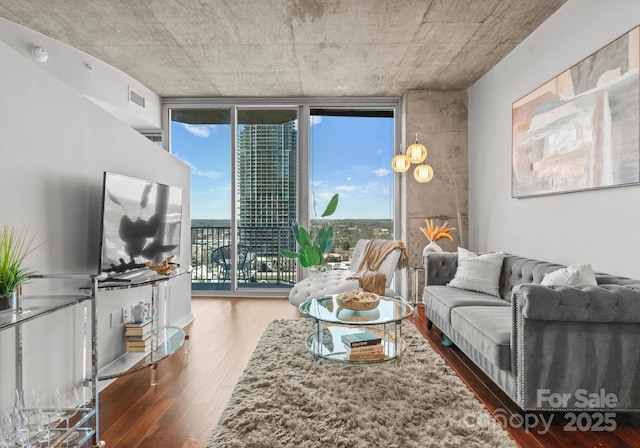 living area featuring plenty of natural light, wood finished floors, visible vents, and floor to ceiling windows