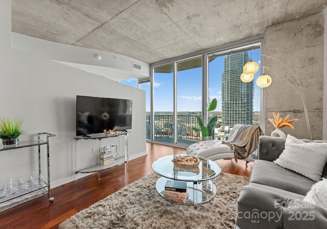 living room featuring expansive windows, wood finished floors, visible vents, and baseboards