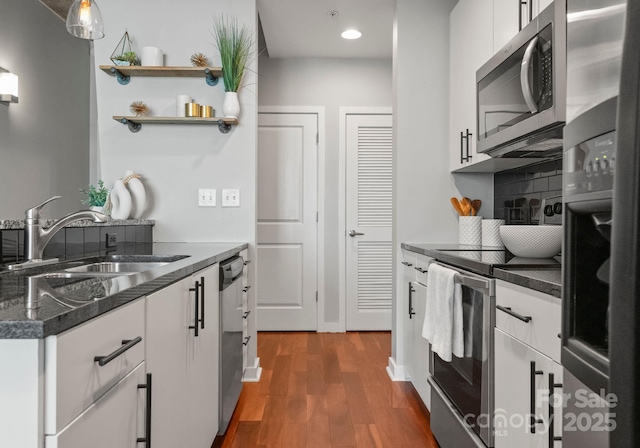 kitchen with appliances with stainless steel finishes, dark wood-type flooring, a sink, and white cabinetry