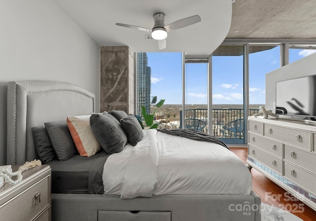 bedroom with access to exterior, expansive windows, a ceiling fan, and wood finished floors