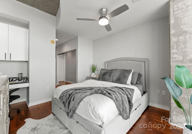 bedroom with ceiling fan, wood finished floors, baseboards, a closet, and built in desk