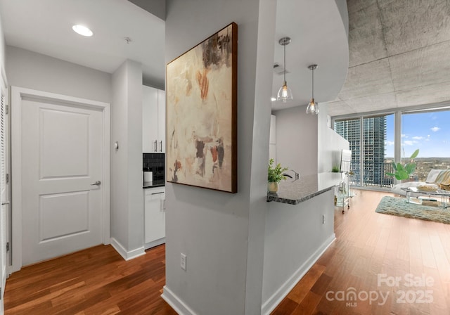 hallway with dark wood-style flooring, visible vents, and baseboards