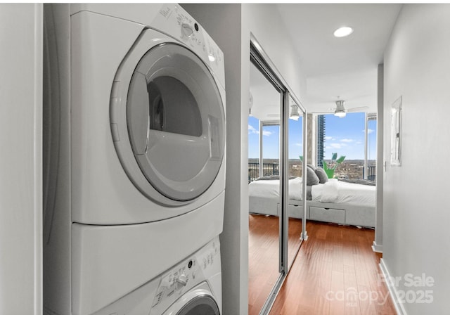 laundry room with ceiling fan, recessed lighting, stacked washer and dryer, laundry area, and wood finished floors