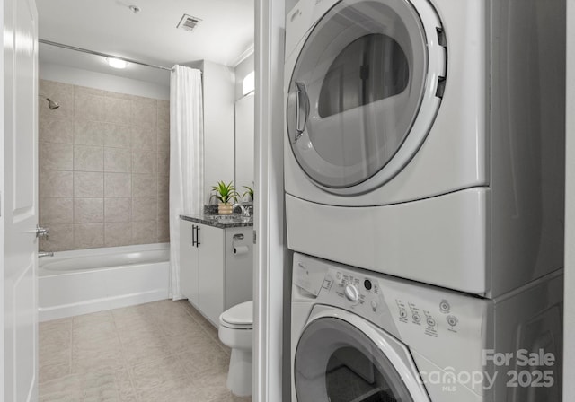 laundry area with light tile patterned floors, laundry area, stacked washing maching and dryer, and visible vents