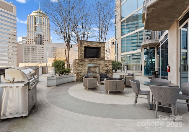 view of patio featuring an outdoor stone fireplace, area for grilling, a city view, and an outdoor kitchen