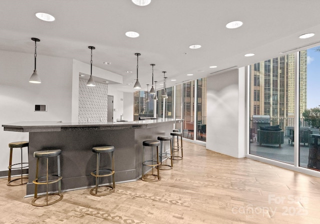 kitchen featuring a breakfast bar, light wood-style flooring, and floor to ceiling windows