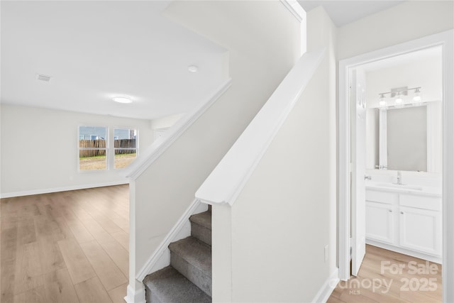 staircase with visible vents, baseboards, and wood finished floors