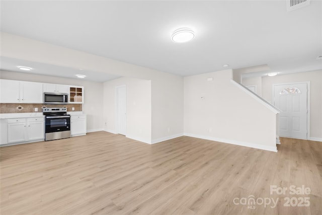 unfurnished living room with light wood-style floors, visible vents, and baseboards