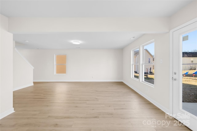 unfurnished room featuring light wood-style flooring, baseboards, and a wealth of natural light