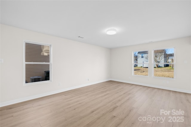 empty room featuring light wood-style floors, visible vents, and baseboards