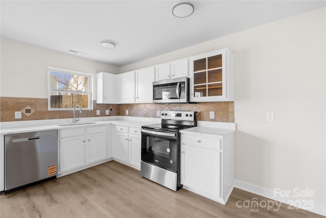 kitchen with stainless steel appliances, a sink, light countertops, and white cabinets