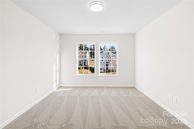 carpeted spare room featuring baseboards