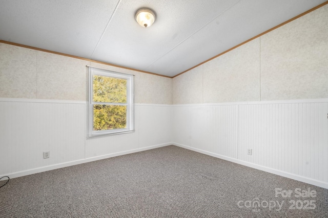 unfurnished room with vaulted ceiling, carpet flooring, and wainscoting