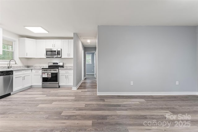 5329 Southampton Rd, Charlotte, NC 28217 - kitchen featuring light wood finished floors, baseboards, white cabinets, stainless steel appliances, and a sink