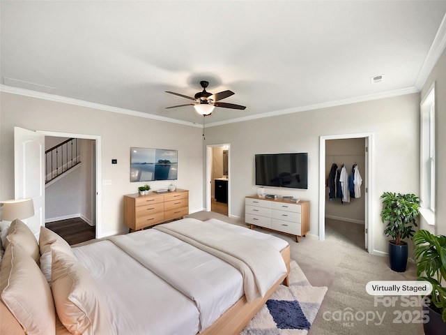 bedroom featuring light carpet, baseboards, a spacious closet, ornamental molding, and a closet